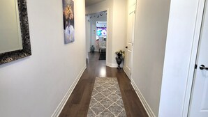 A hallway with a wooden floor, a rug, a painting, and a door. - Spacious 4 Bedroom House in Angus (Angus)