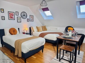 A modern bedroom with a large bed, a smaller bed, a dining table with chairs, and a skylight. - Ideal Studio Loft 30min to Central London (Wembley)