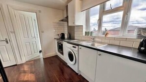 A compact kitchen with a washing machine, a sink, and a window with a view.