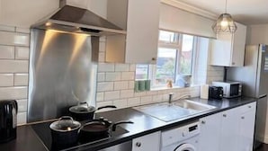 A modern kitchen with stainless steel appliances, a window with a view, and a hanging light fixture.
