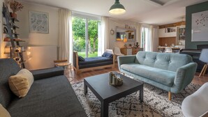 A modern living room with a sofa, a coffee table, and a dining area with a table and chairs. - Villa Juliette - Welkeys (Écully)