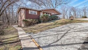 A single-story house with a brown exterior and a covered porch. - Private Suite, Sleep and Bike- Seconds 2  trail! Private Basement Apartment. (Bella Vista)