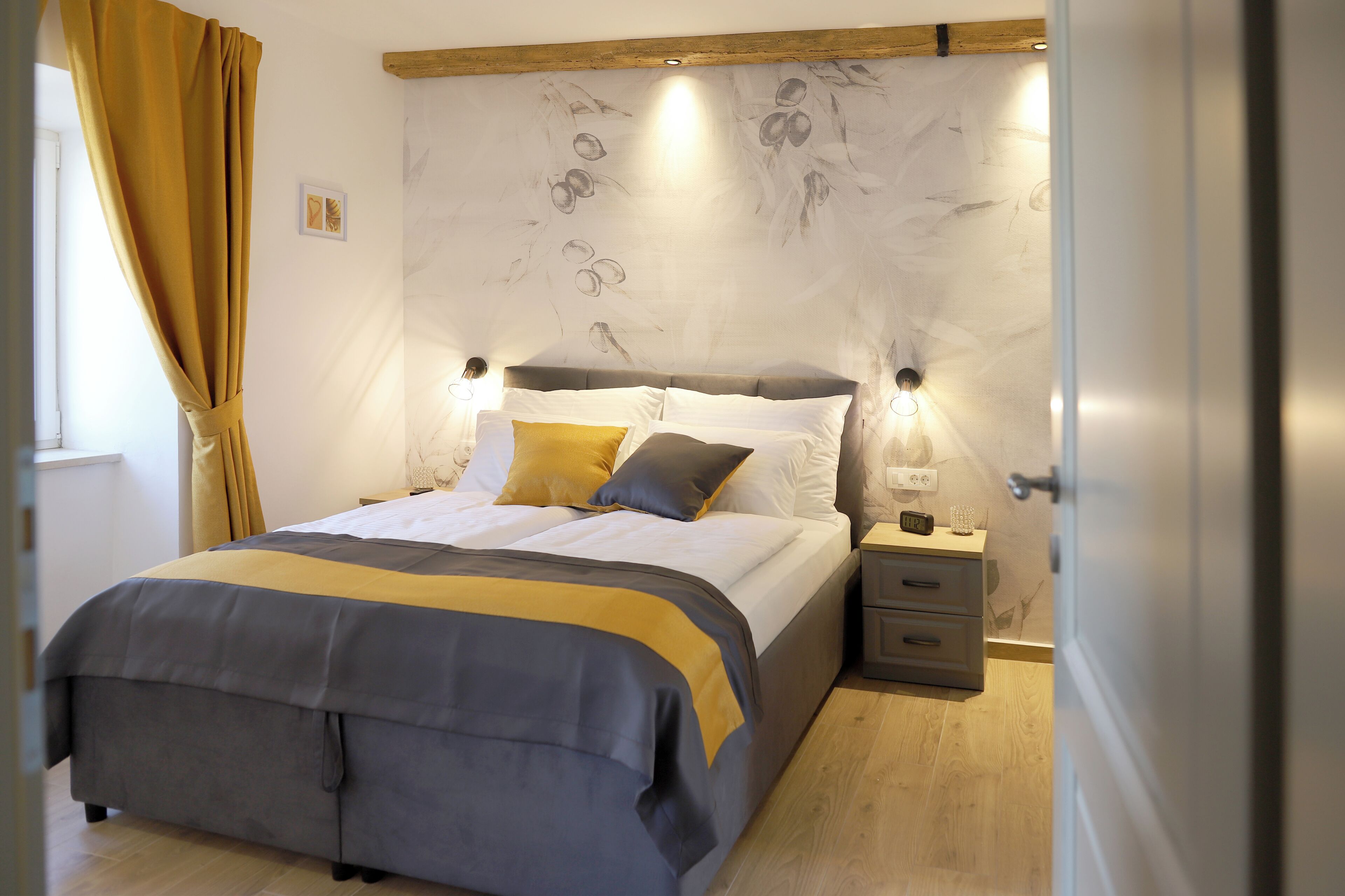 A modern bedroom with a bed, bedside tables, and a headboard with wall art.
