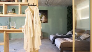 Ein Schlafzimmer mit zwei Betten, einem Holztisch mit Lampe und einer grünen Wand mit Pflanze.