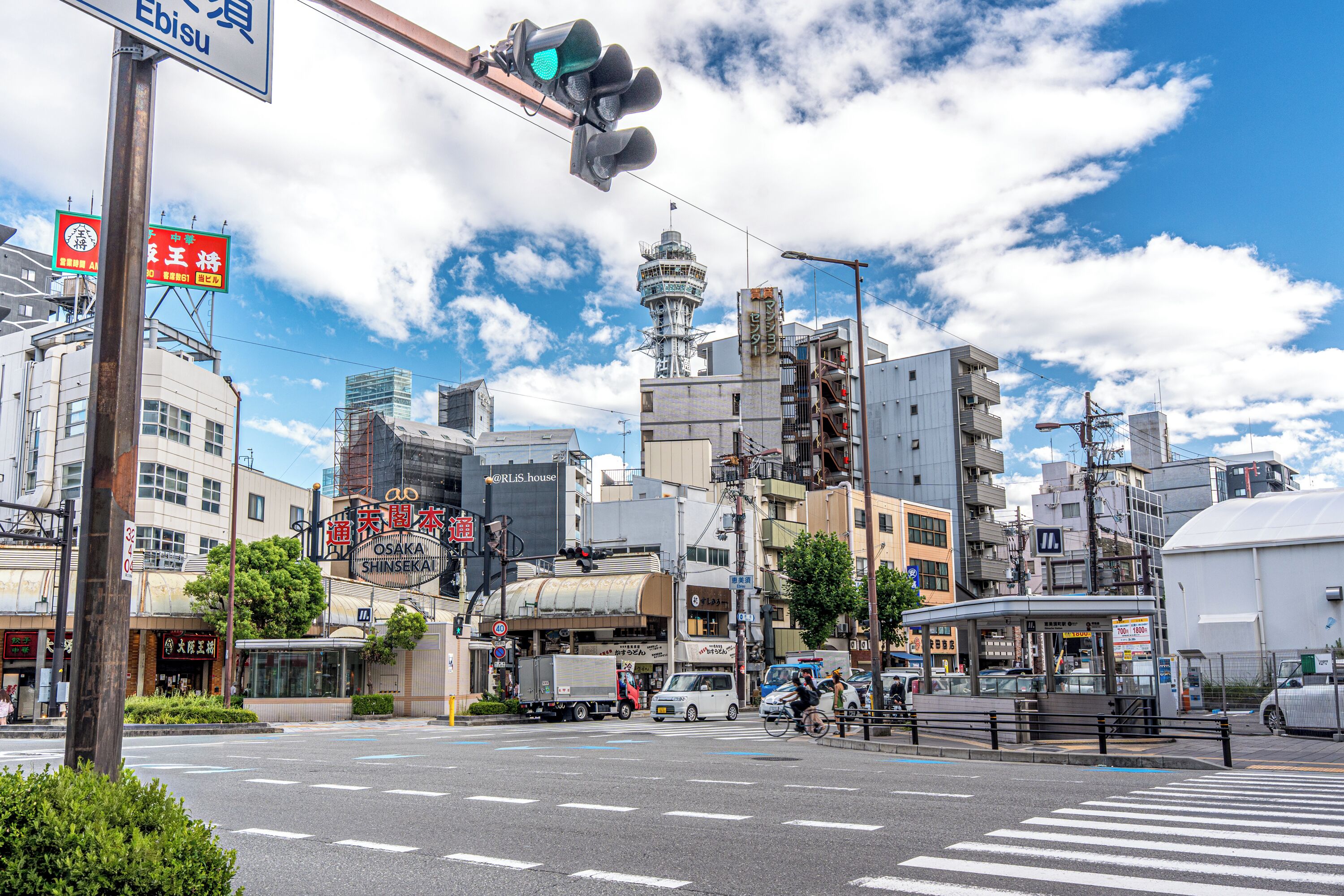 A city intersection with traffic lights, buildings, and a clear sky.
