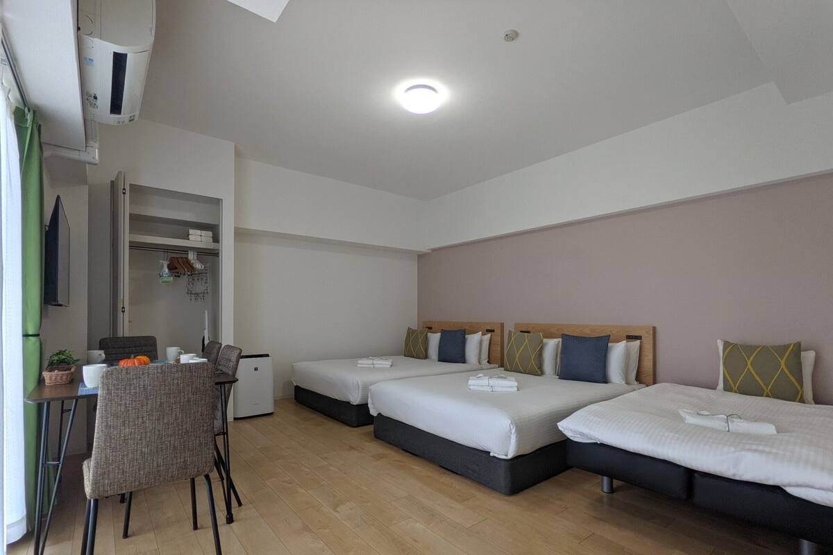 Ein Hotelzimmer mit zwei Betten, einem Esstisch, einem Stuhl und einer Küchenzeile.