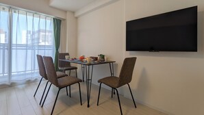 Un comedor moderno con una mesa, sillas y un televisor de pantalla plana montado en la pared.