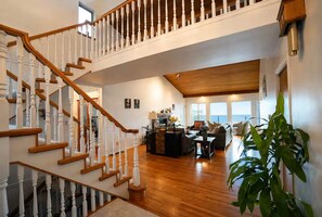 Un vaste espace de vie agrémenté d’un escalier en bois, d’une cheminée et offrant une vue sur l’extérieur.