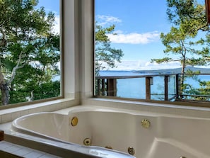 A bathtub with a view of a lake and trees.