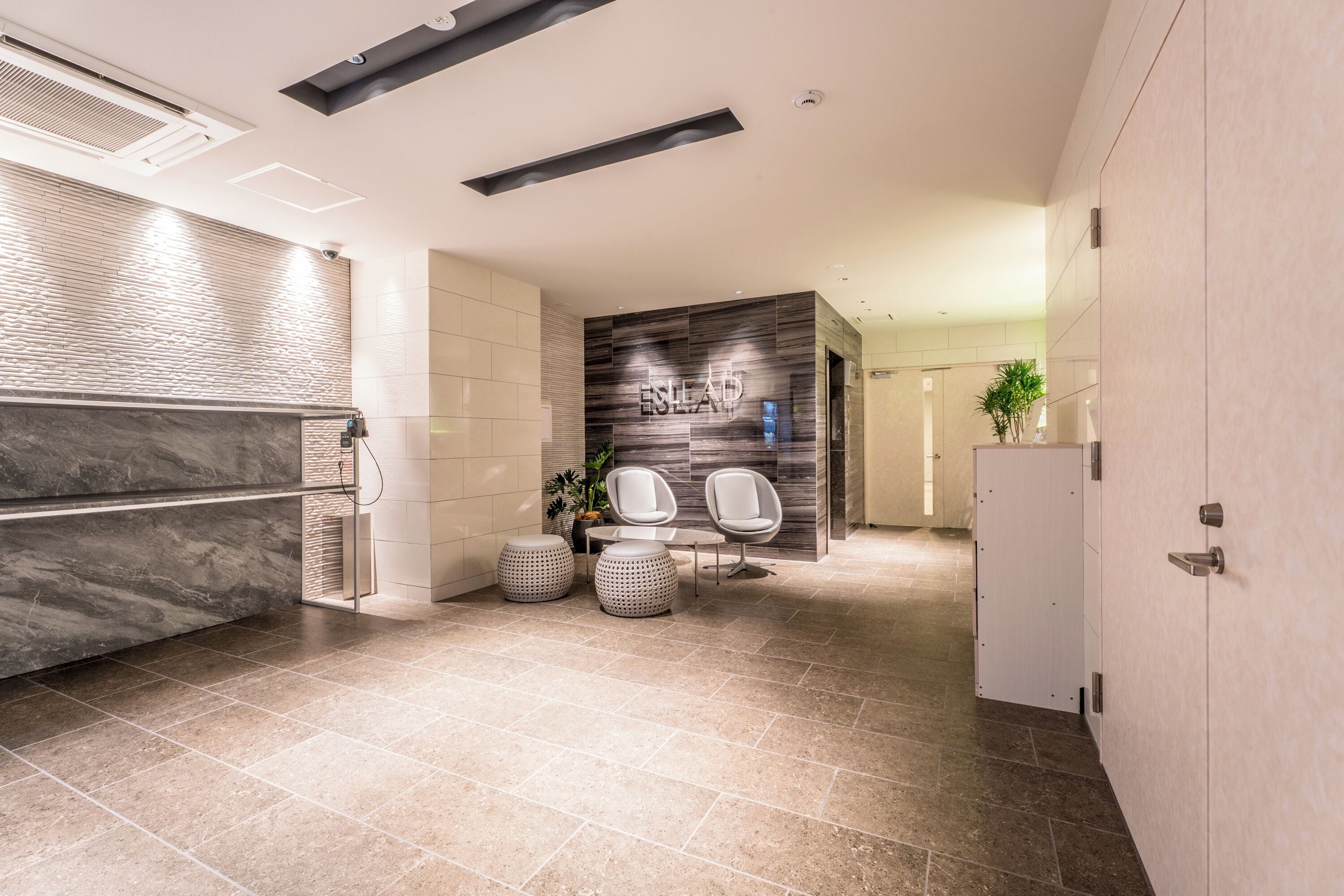 A modern bathroom with a marble vanity, a wall-mounted sink, and a seating area with two chairs.
