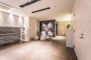 Un baño moderno con tocador de mármol, lavamanos empotrado y una zona de estar con dos sillas.