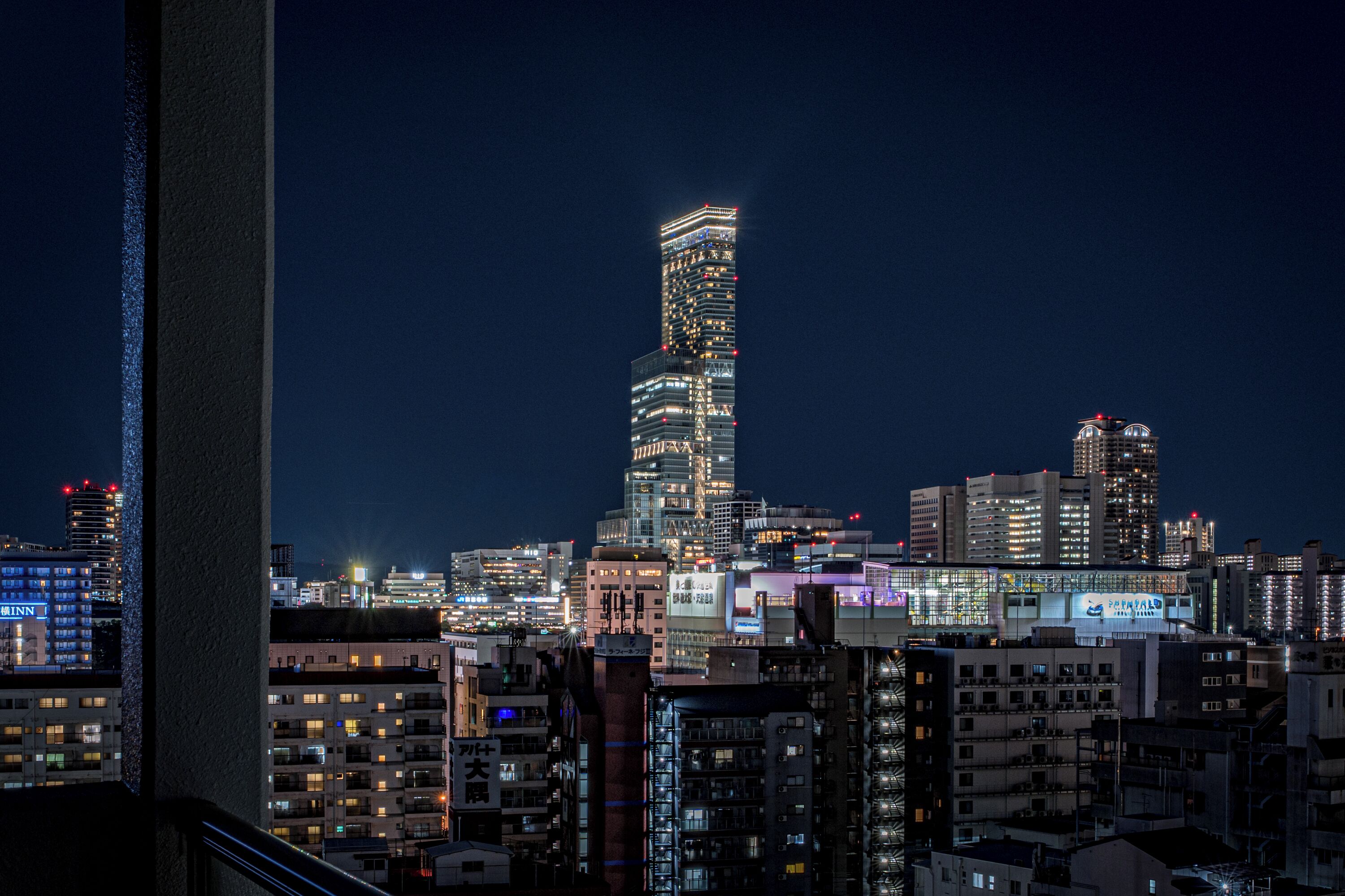 A nighttime cityscape with a prominent skyscraper featuring a unique twisted design.