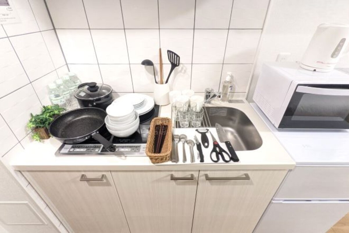 A kitchen with a microwave, stove, sink, and various utensils and dishes.