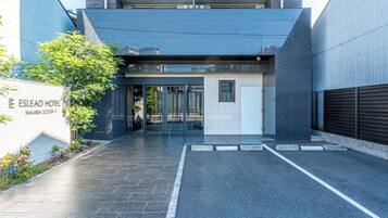 The entrance of the Eslead Hotel with a modern design, including a glass door entrance and a paved driveway.