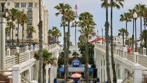 A coastal promenade with palm trees, a bridge, and a seafood restaurant.