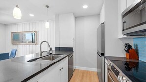 A modern kitchen with a large island, stainless steel appliances, and pendant lighting.