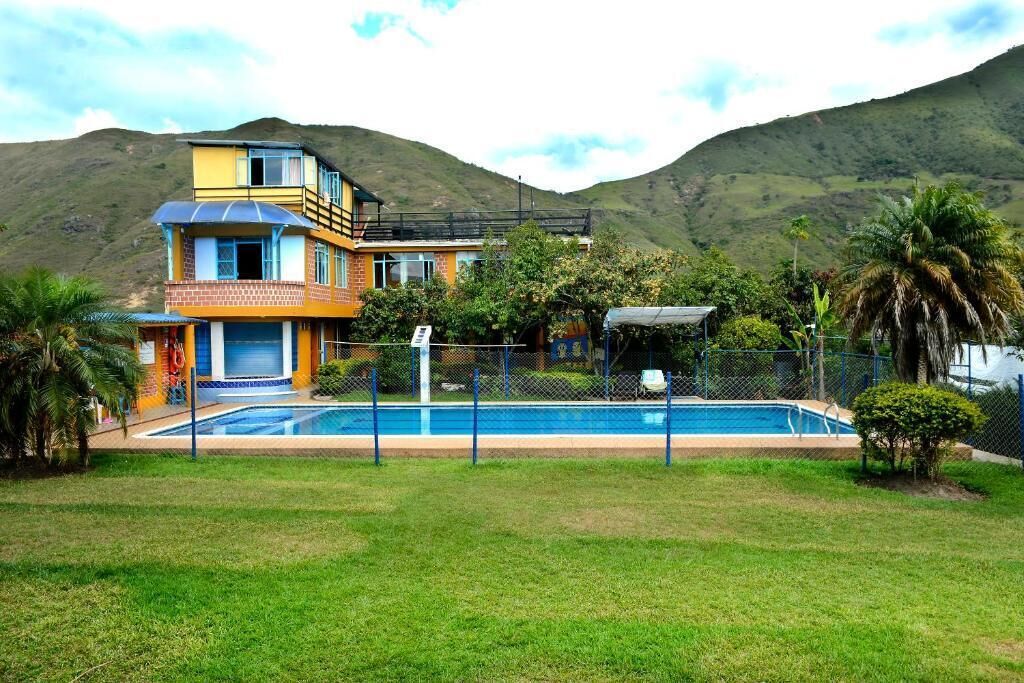 Ein zweigeschossiges Haus mit Swimmingpool, umgeben von einem eingezäunten Garten und Palmen.