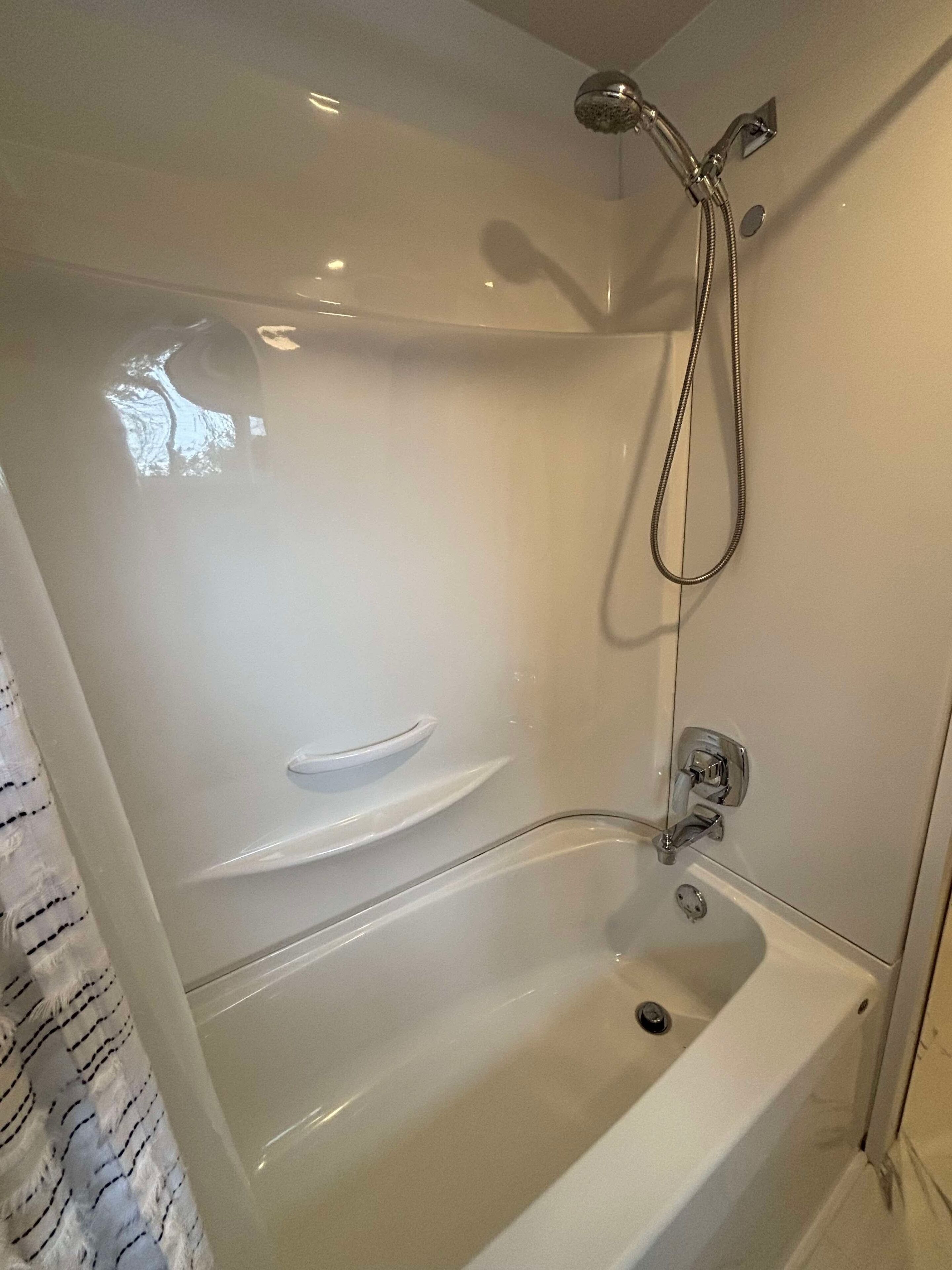 Et moderne badeværelse med brusebad bag glasvæg, badekar og et vaskeskab med spejl.