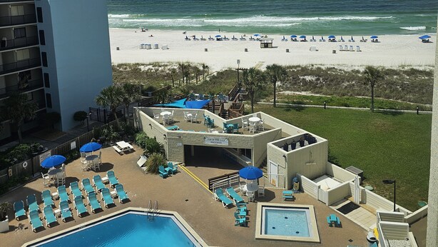 A rooftop pool area with multiple pools and lounge chairs, overlooking a beach with umbrellas and lounge chairs. - BEACH & POOL VIEW!! LOCATED DIRECTLY ON THE BEACH!! (Panama City Beach)