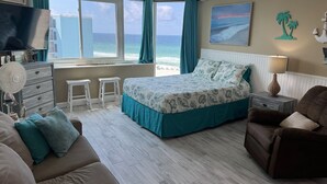 A bedroom with a bed, a TV, a fan, a nightstand, and a view of the beach. - BEACH & POOL VIEW!! LOCATED DIRECTLY ON THE BEACH!! (Panama City Beach)