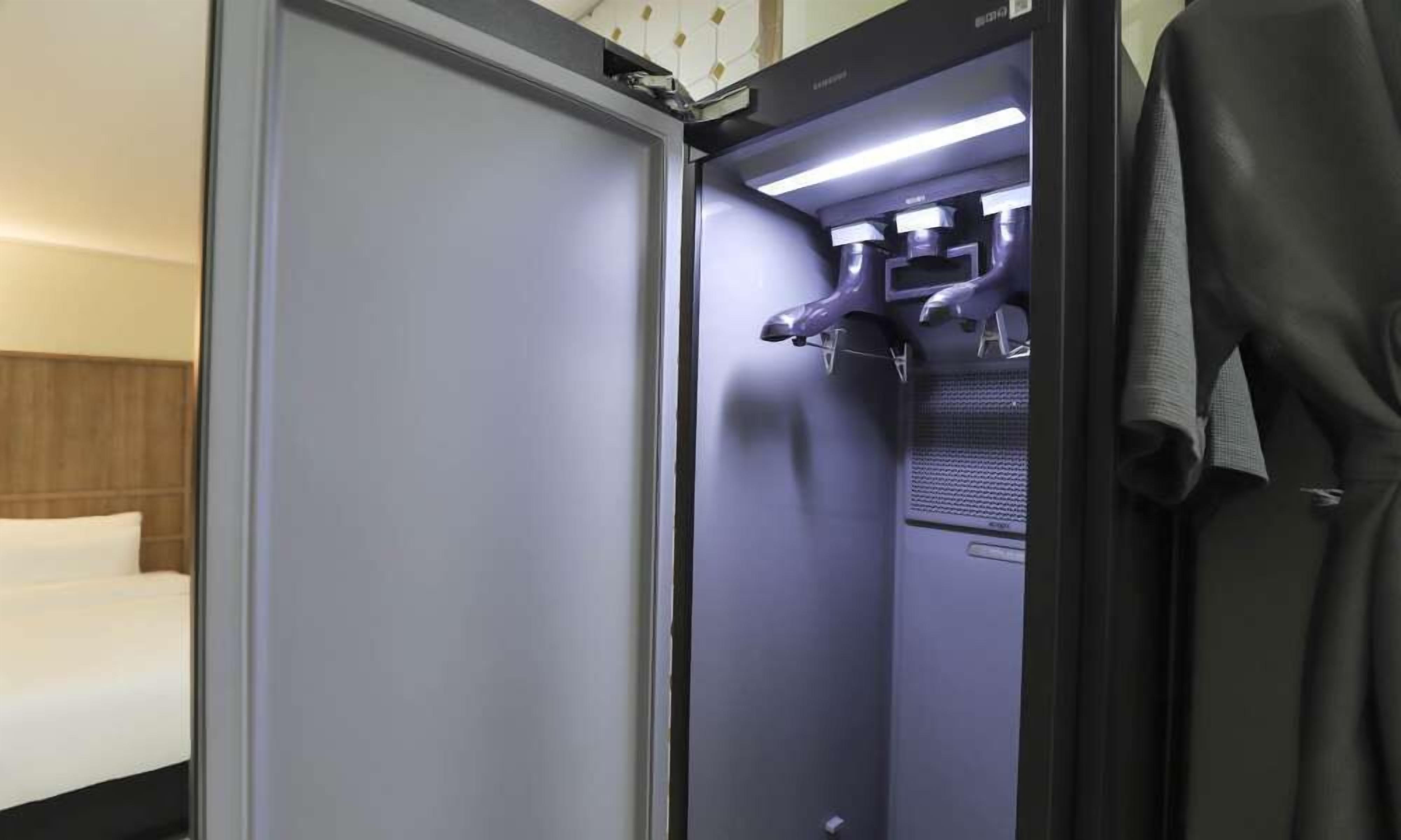 A hotel room with a bed, a wardrobe, and a shower area with a towel rack.