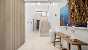 A modern interior with a wooden floor, a staircase, and a large painting on the wall.