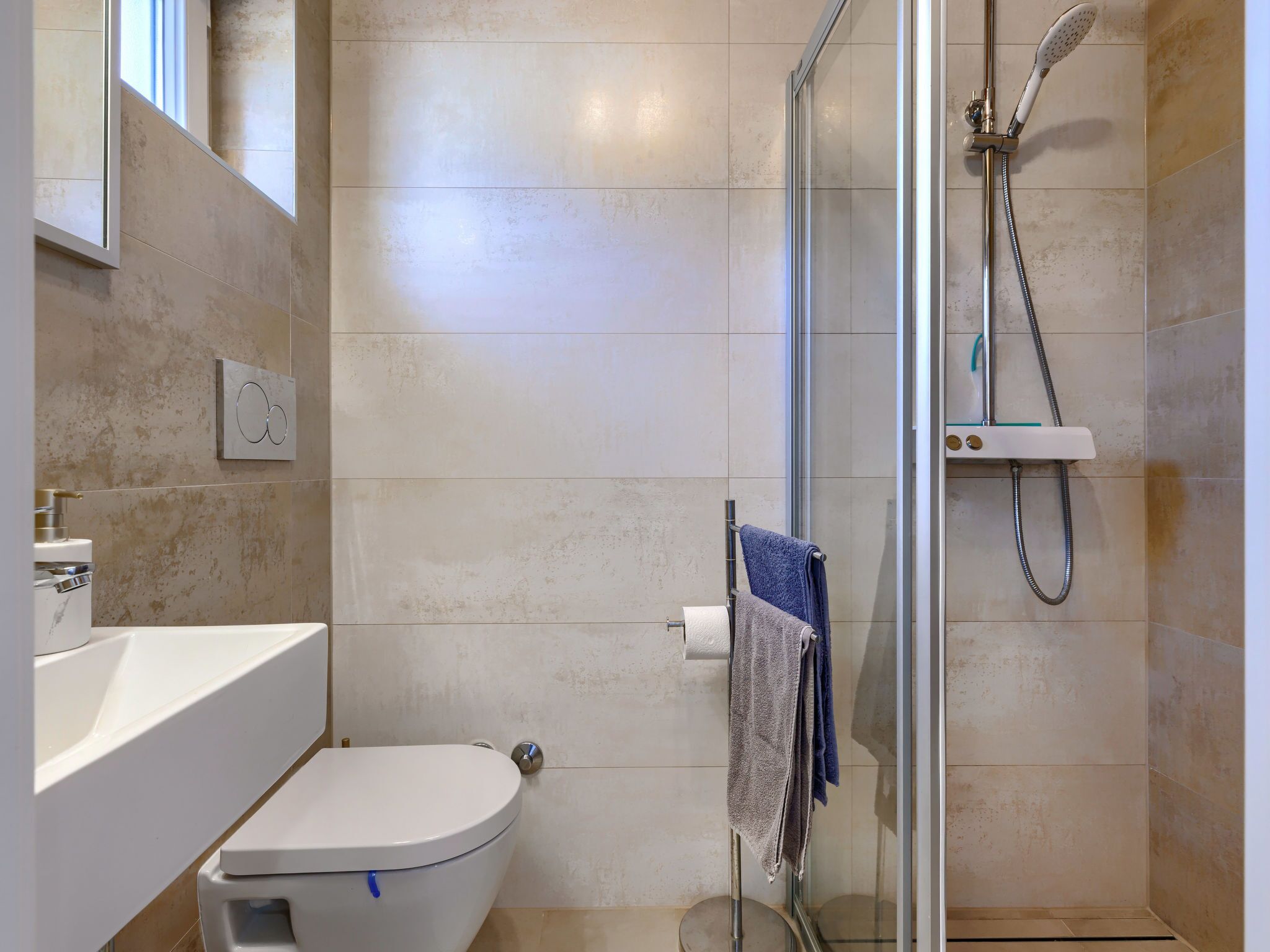 Et badeværelse med toilet, håndvask og brusebad.