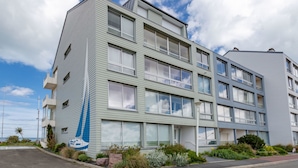 A multi-story building with a modern design, featuring large windows and a balcony on the second floor.