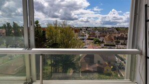 A view from a window overlooking a residential area with houses and trees.