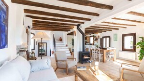 A spacious living area with a sofa, chairs, a coffee table, and a fireplace. - Magnificent rustic house with pool, garden, and views (Acequias)