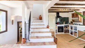 A staircase leading to a kitchen with exposed wooden beams, a tiled backsplash, and various kitchen utensils and cookware. - Magnificent rustic house with pool, garden, and views (Acequias)