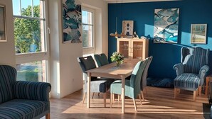 Ein Essbereich mit Holztisch und Stühlen, einer blauen Akzentwand und Kunstwerken.