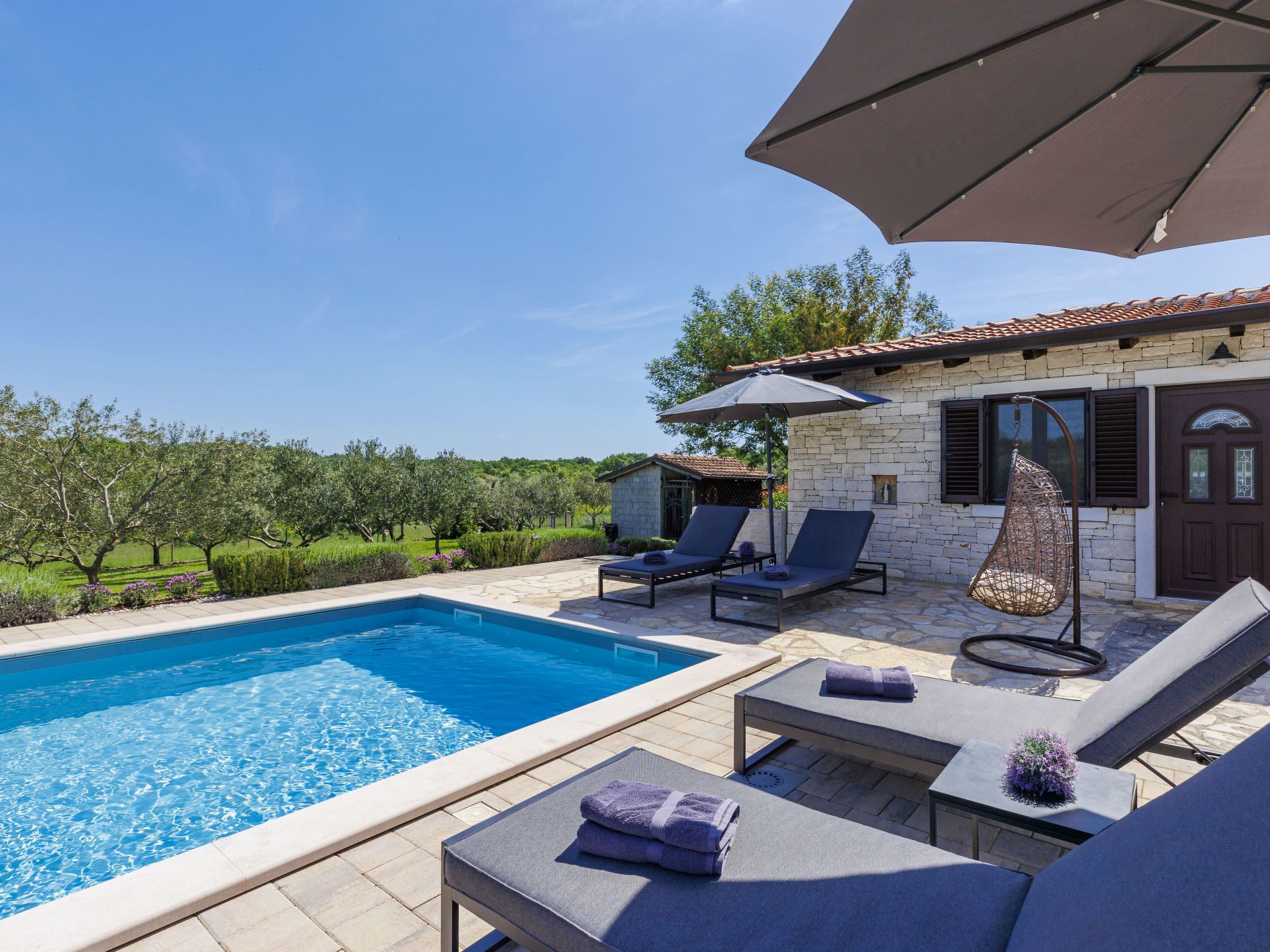 A poolside area with lounge chairs, a table, and an umbrella.