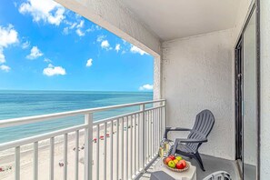 A balcony with a view of the ocean, a chair, and a table with fruit and a glass of champagne. - Sea Mist 21004 (Myrtle Beach)