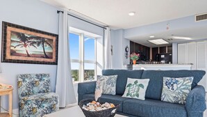 A living room with a blue sofa, a chair, a table, and a framed picture on the wall. - Bay Watch 1441 (North Myrtle Beach)