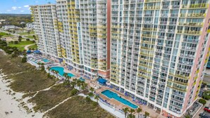 A high-rise hotel with multiple balconies, a pool area, and a beach view. - Bay Watch 1441 (North Myrtle Beach)