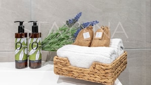 Un mobile bagno con piano bianco, due flaconi di shampoo, un asciugamano bianco e un cesto in vimini contenente un asciugamano.