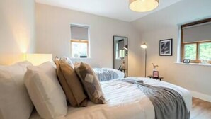 A bedroom with a bed, a bedside lamp, a window, and a mirror.