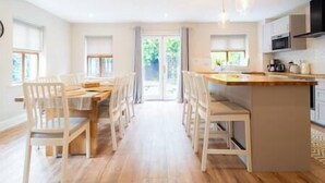 A spacious kitchen with a central island, white cabinetry, and a dining area with chairs and a table.