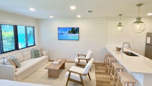 A modern, well-lit room with a sofa, chairs, a coffee table, and a kitchen area with stools. - Prime 30A Location/EZ Beach Access/Quiet Pool/Fast Wifi  (Santa Rosa Beach)