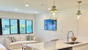 A modern kitchen with white cabinetry, a central island with a sink, and pendant lighting. - Prime 30A Location/EZ Beach Access/Quiet Pool/Fast Wifi  (Santa Rosa Beach)