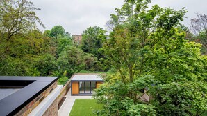 Una casa moderna con techo plano, un pequeño jardín y un muro de ladrillo.