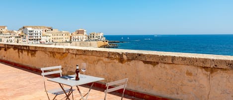 Terraza con mesa y sillas con vista a un paisaje urbano costero.