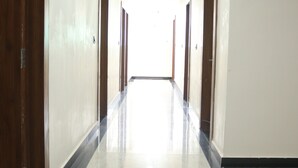 A long, narrow hallway with wooden doors on both sides and a shiny tiled floor. - Hotel Maxsun Gwalior (Gwalior)