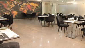 A modern dining area with black chairs and tables, a large fruit and vegetable mural on the wall, and a clean, polished floor. - Hotel Maxsun Gwalior (Gwalior)
