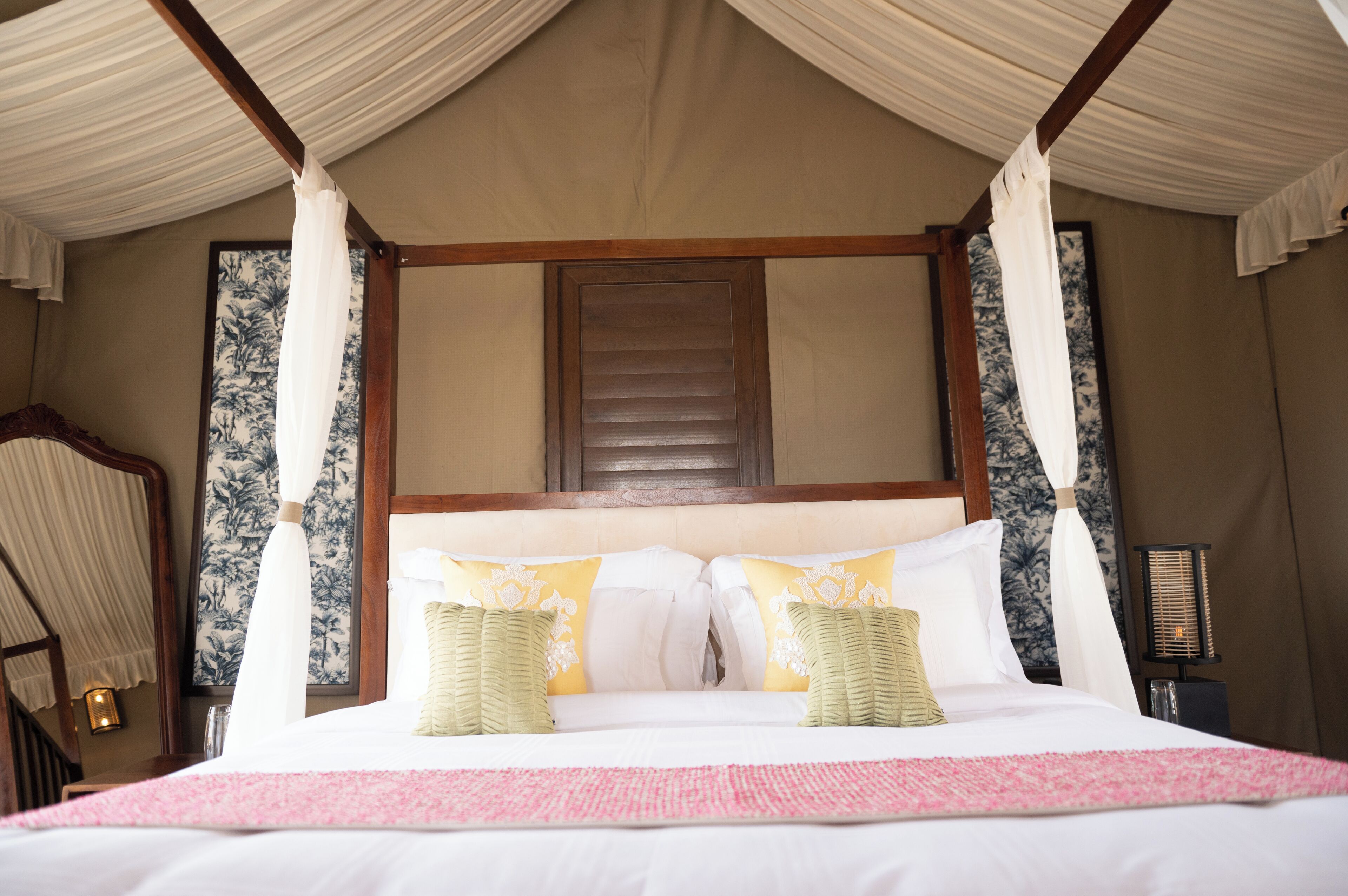 Ein Bett mit Baldachin, einem hölzernen Kopfteil und einer Wand mit Blumenmuster.