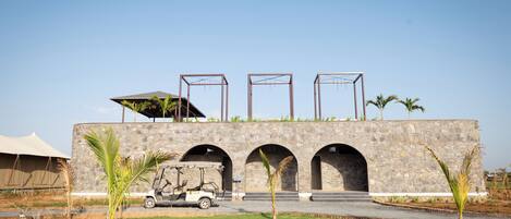 A building with a stone facade, three arched openings, and a covered area on the roof.