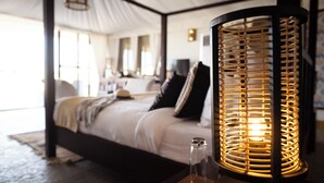 Een goed verlichte slaapkamer met een bed, een nachtkastje met een lamp en een groot raam.