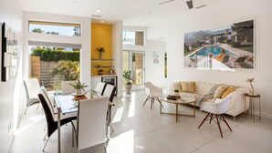 A spacious living area with a dining table, chairs, a sofa, and a ceiling fan. - Modernism week gem STR 003734 (Palm Springs)