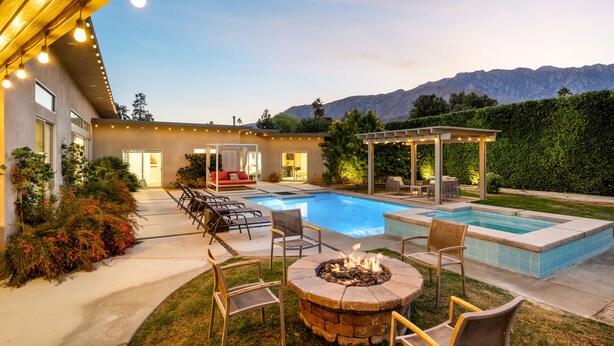 A backyard with a pool, outdoor seating, and a fire pit. - Modernism week gem STR 003734 (Palm Springs)